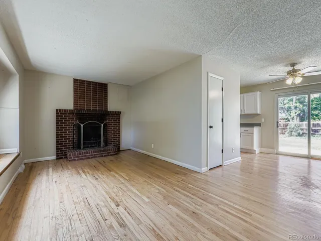 an empty room with wooden floor fireplace and windows