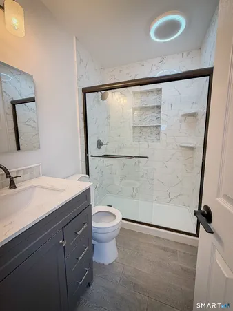 a bathroom with a granite countertop sink toilet a mirror and shower