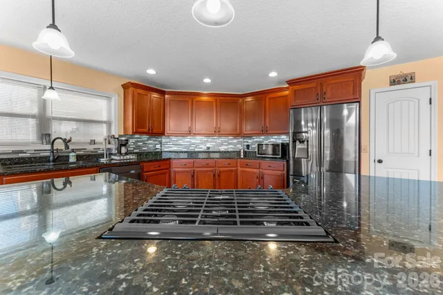 a kitchen with stainless steel appliances granite countertop a stove a sink and a refrigerator