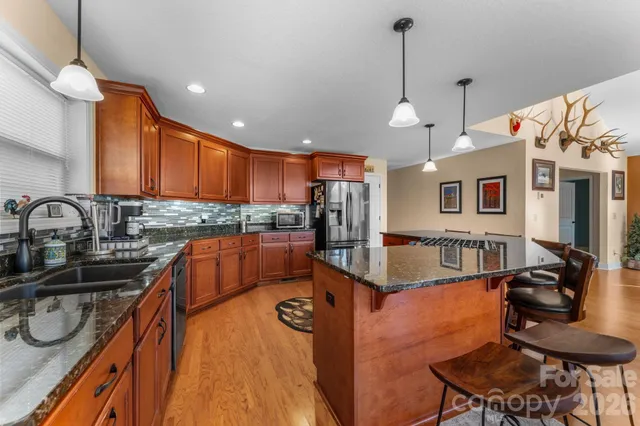 a kitchen with stainless steel appliances granite countertop a sink a stove and a wooden floors