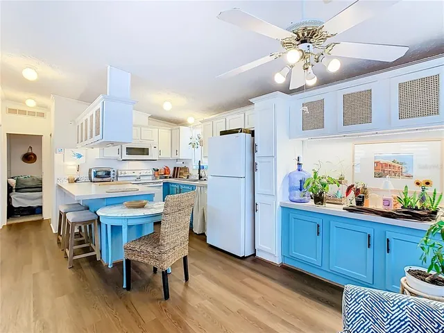 a kitchen with stainless steel appliances kitchen island granite countertop a refrigerator a stove a sink dishwasher and a dining table with wooden floor