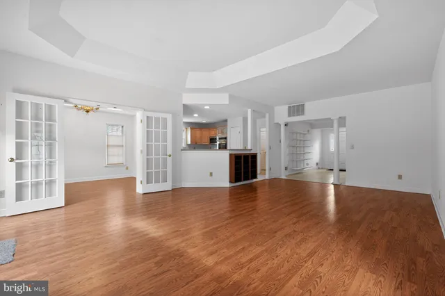 a view of empty room with wooden floor and kitchen