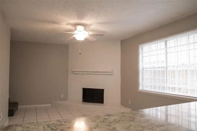 a view of a livingroom with a fireplace a ceiling fan and windows