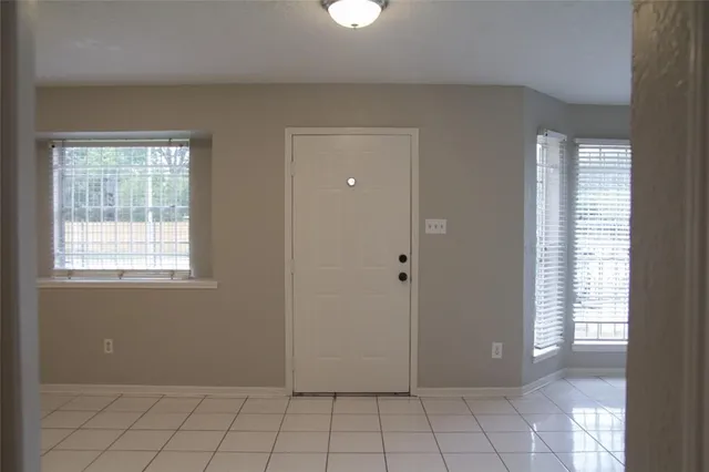 a view of an empty room with window and cabinet area