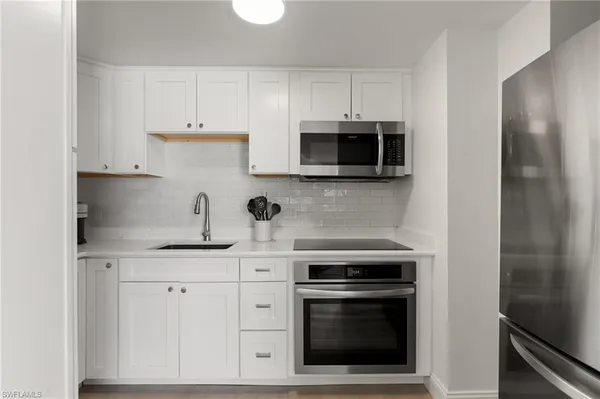 a kitchen with granite countertop white cabinets and stainless steel appliances