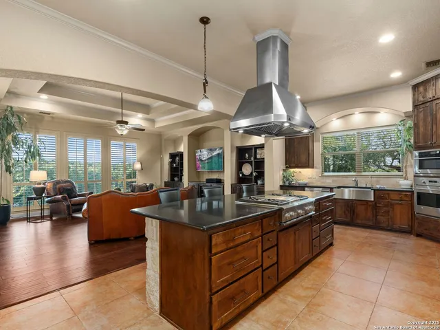 a kitchen with stainless steel appliances kitchen island granite countertop a refrigerator a stove a sink a dining table and chairs with wooden floor