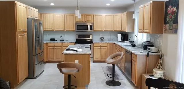 a kitchen with stainless steel appliances granite countertop a sink a stove and a refrigerator