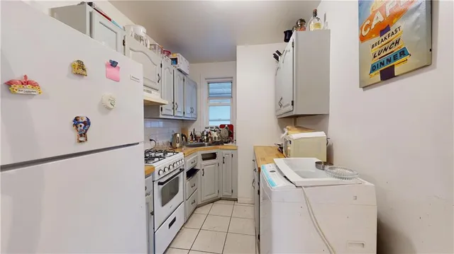 a kitchen with stainless steel appliances a white refrigerator stove and white cabinets
