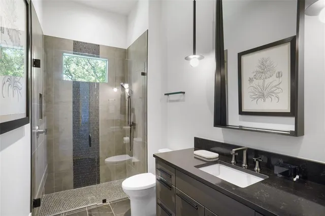 a bathroom with a granite countertop sink toilet a mirror a vanity and shower