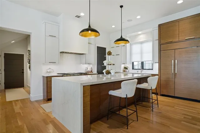 a kitchen with stainless steel appliances granite countertop a table chairs sink and wooden floor