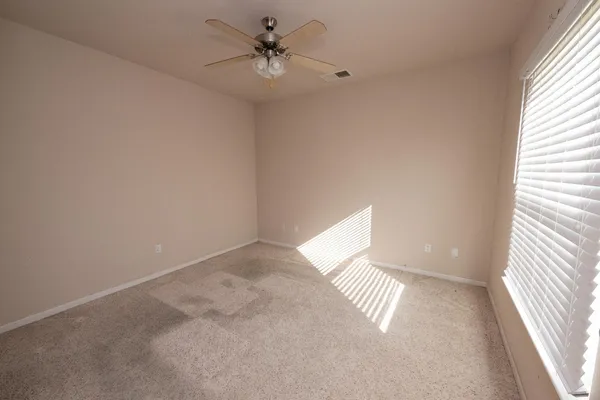 an empty room with a window and a fan