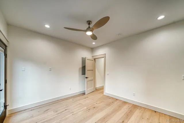 an empty room with wooden floor ceiling fan and window