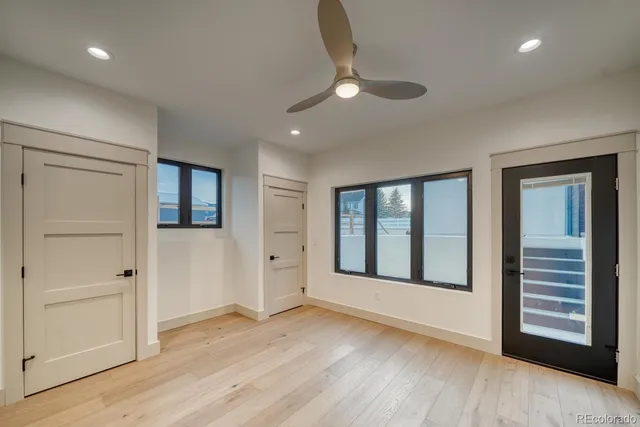 an empty room with wooden floor cabinet and windows