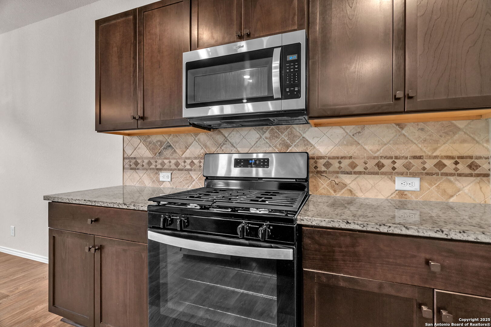 105 Honors Street Floresville, TX 78114 - Photo 12 of 36 a kitchen with granite countertop cabinets stainless steel appliances and wooden floor