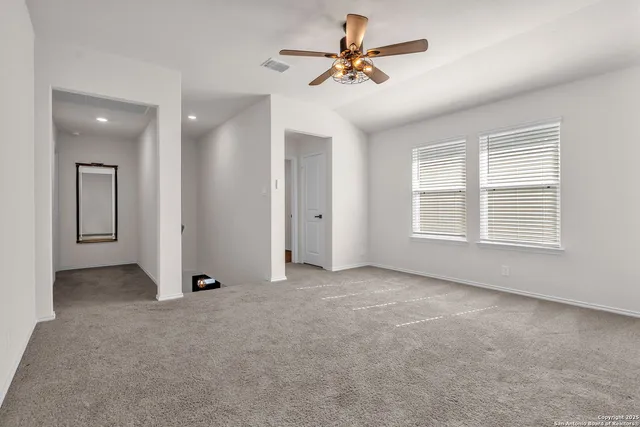 an empty room with chandelier fan and windows