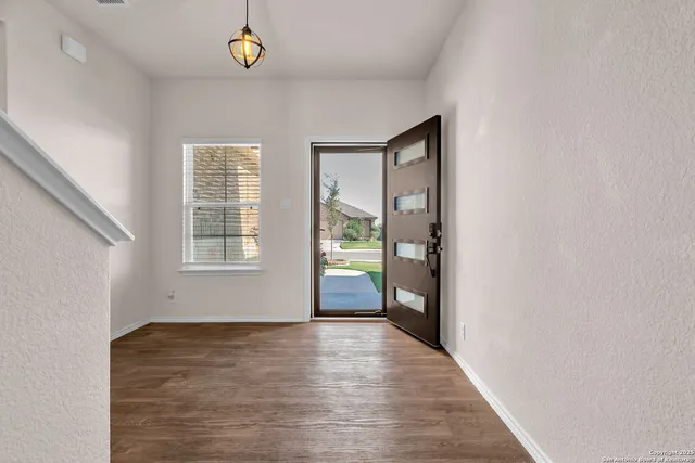 a view of an empty room with wooden floor and a window