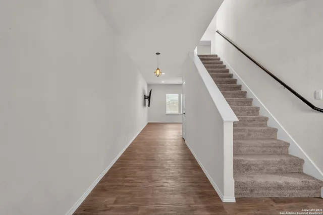 a view of staircase with wooden floor and lots of frames on wall