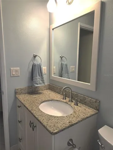a bathroom with a granite countertop sink toilet and mirror