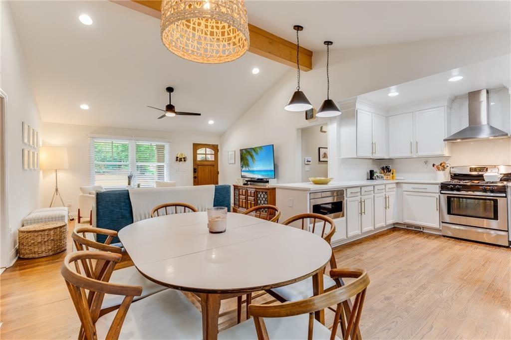 2357 Cortez Way Northeast Brookhaven, GA 30319 - Photo 10 of 32 a kitchen with stainless steel appliances kitchen island granite countertop a stove a sink a dining table and chairs with wooden floor