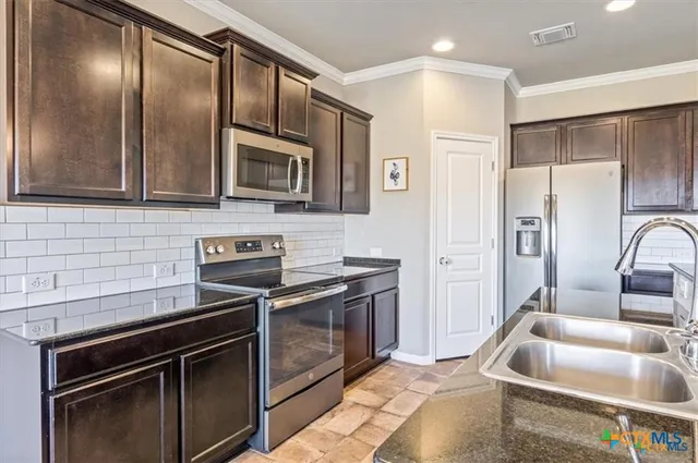 a kitchen with stainless steel appliances granite countertop a stove microwave and refrigerator