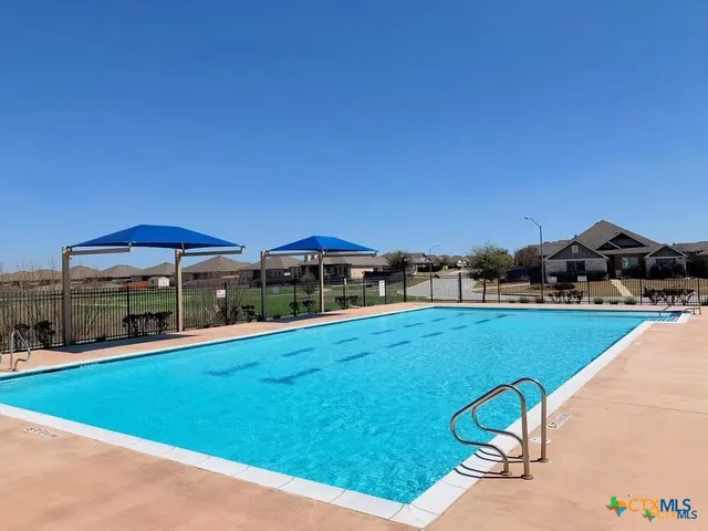 a view of a swimming pool with lawn chairs under an umbrella