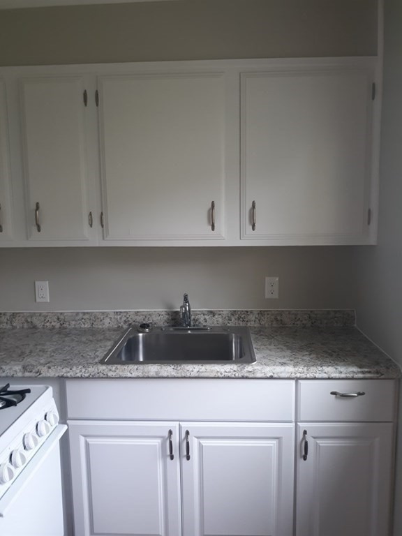107-121 Winter Street Fall River, MA 02720 - Photo 6 of 10 a kitchen with white cabinets and a stove