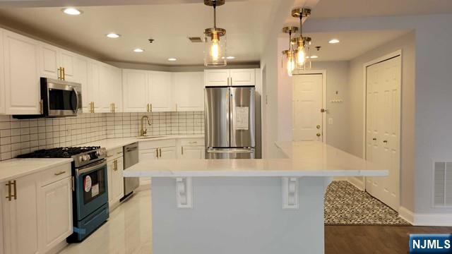 302 Stockton Court Edgewater, NJ 07020 - Photo 4 of 15 a kitchen with stainless steel appliances granite countertop a sink a stove and a refrigerator