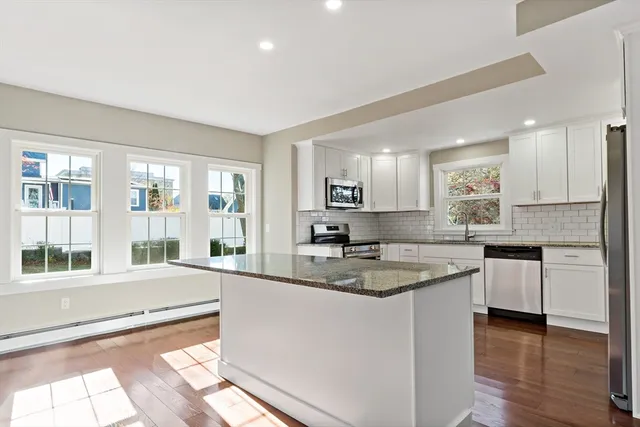 a large kitchen with granite countertop a large window cabinets and stainless steel appliances