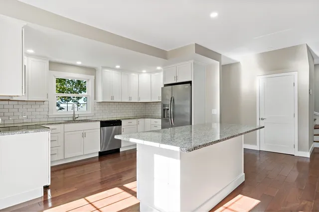 a kitchen with stainless steel appliances granite countertop a refrigerator a sink a stove a microwave and white cabinets