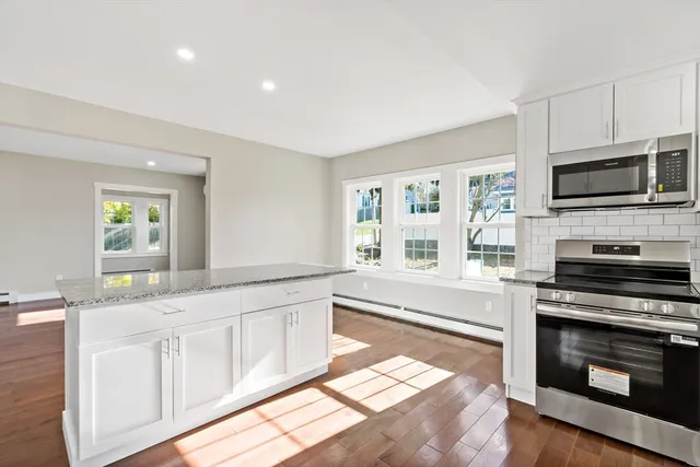 a kitchen with granite countertop a stove top oven a sink and a granite counter tops with wooden floors