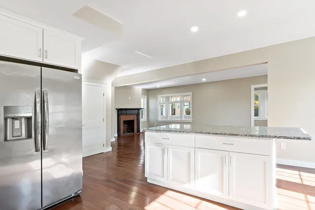 a kitchen with granite countertop a refrigerator a sink and white cabinets