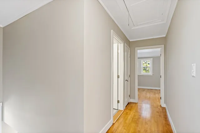 a view of a hallway with wooden floor and a bathroom