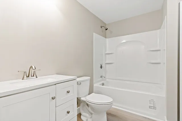 a bathroom with a toilet a sink a mirror a bathtub and vanity