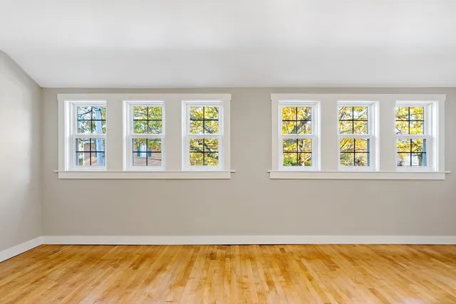 a view of an empty room with a window and hardwood floor