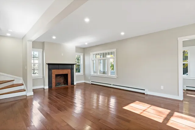 a view of empty room with fireplace and wooden floor