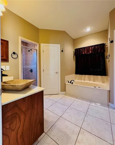 a bathroom with a tub a sink and a large mirror
