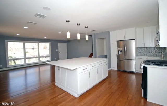 a large kitchen with a large counter top a sink stainless steel appliances and cabinets