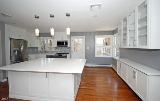 a view of a kitchen with kitchen island a sink wooden floor and stainless steel appliances