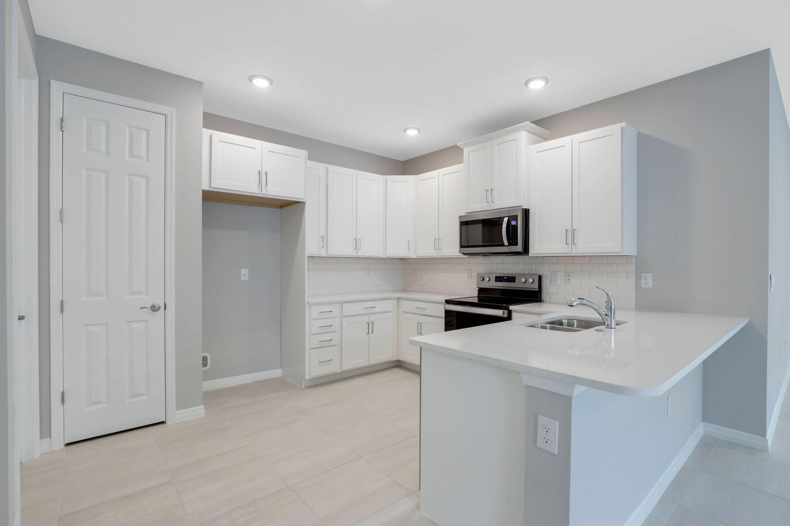 1212 Enbrook Loop Naples, FL 34114 - Photo 9 of 45 a kitchen with white cabinets and stainless steel appliances