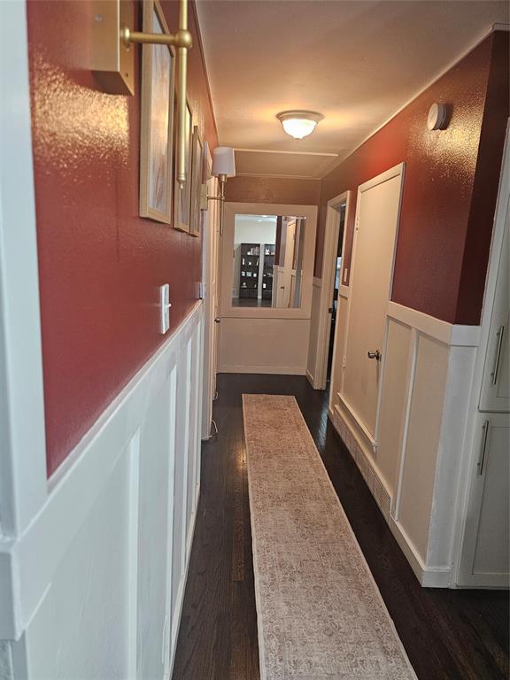 9911 Ferguson Road Dallas, TX 75228 - Photo 8 of 18 Hallway featuring dark wood-style floors, wainscoting, and a decorative wall
