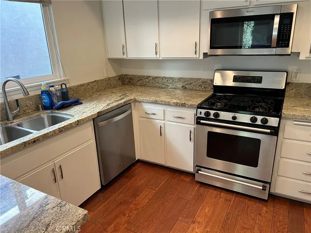 a kitchen with granite countertop wooden cabinets stove and sink