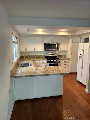 a kitchen with granite countertop a refrigerator and a stove top oven