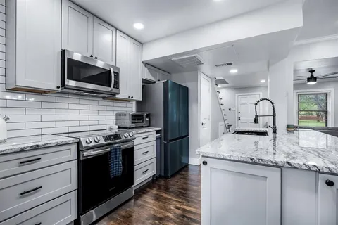 a kitchen with stainless steel appliances granite countertop a stove top oven a sink dishwasher a refrigerator and a microwave