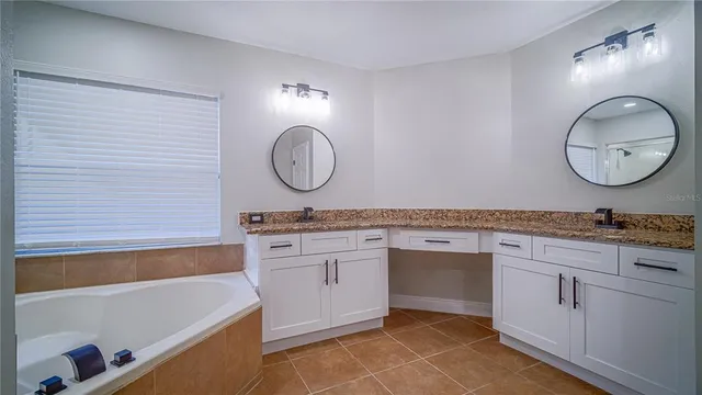 a bathroom with a granite countertop sink a mirror and a bathtub
