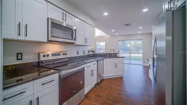 a large kitchen with stainless steel appliances granite countertop a stove and a wooden floors