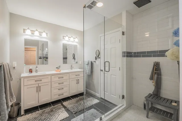 a spacious bathroom with a double vanity sink a mirror a shower and a window