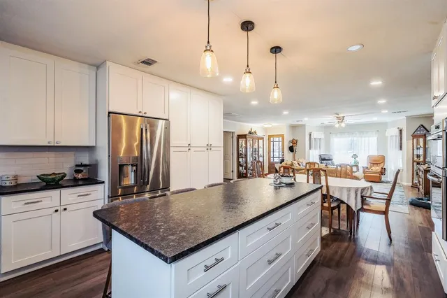 a kitchen with stainless steel appliances granite countertop a kitchen island a stove a table and chairs