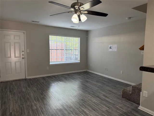 a view of a room with wooden floor and a ceiling fan