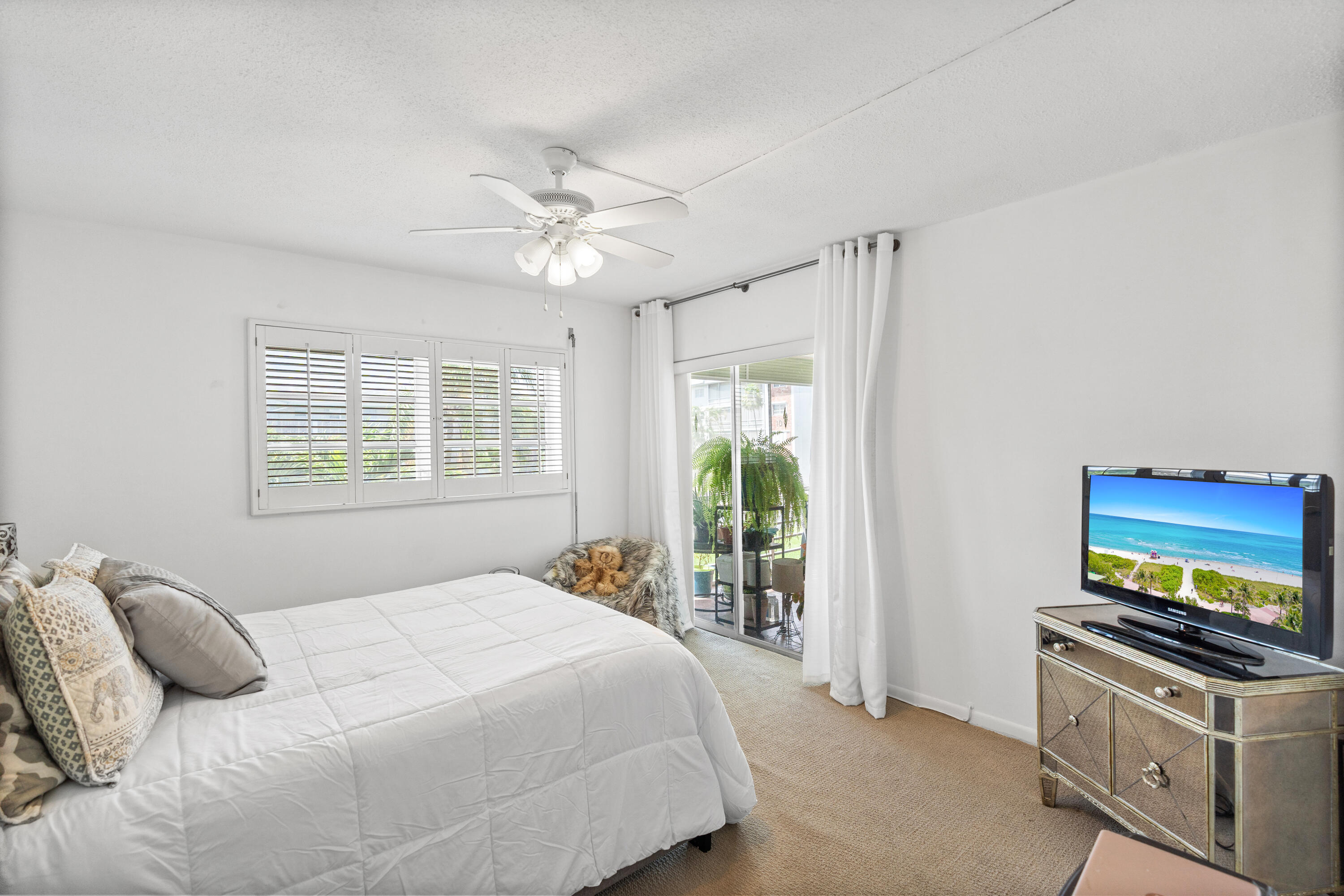 25 Southeast 13th Street, Unit B3 Boca Raton, FL 33432 - Photo 14 of 26 a bedroom with a bed and a flat tv screen on dresser