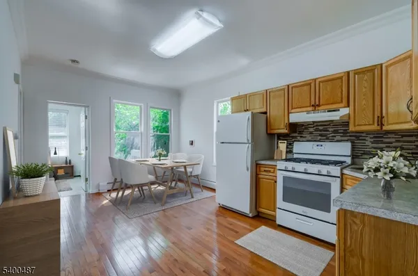 a kitchen with a refrigerator a stove top oven a dining table and chairs with wooden floor